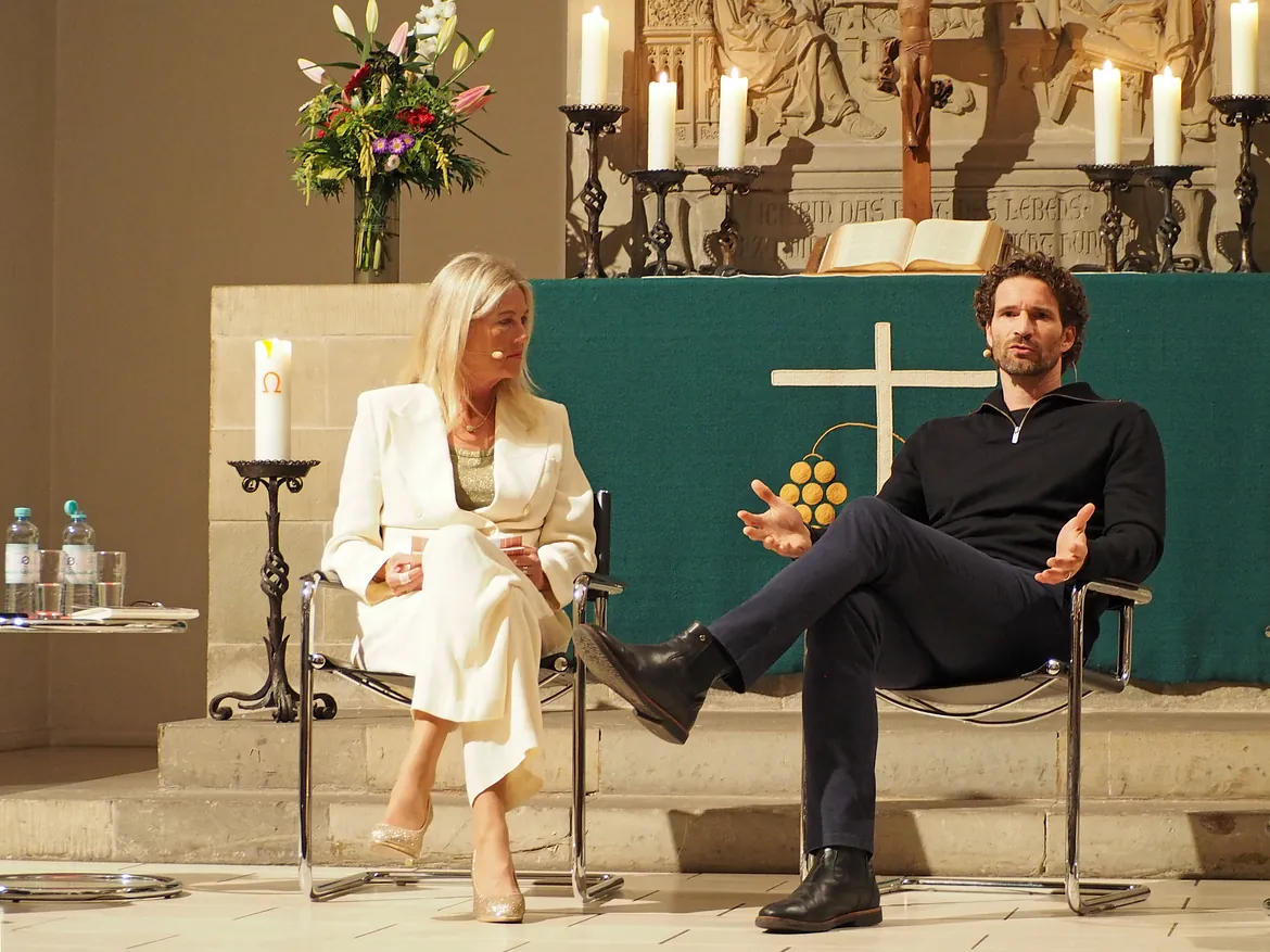 Zwei Personen auf Bühne vor Altar.