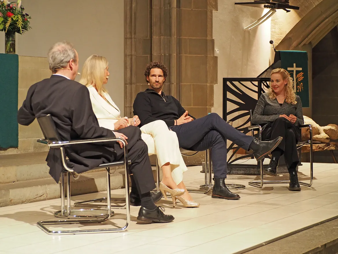 Vier Personen auf Bühne im Gespräch.